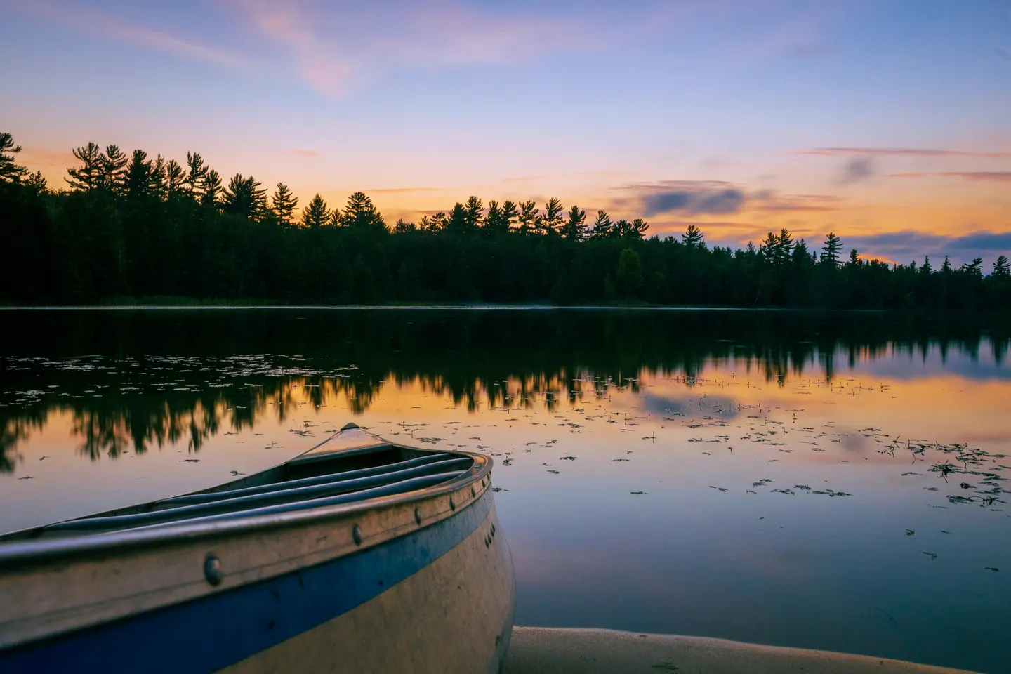 Canoe on a still forest lake at dusk