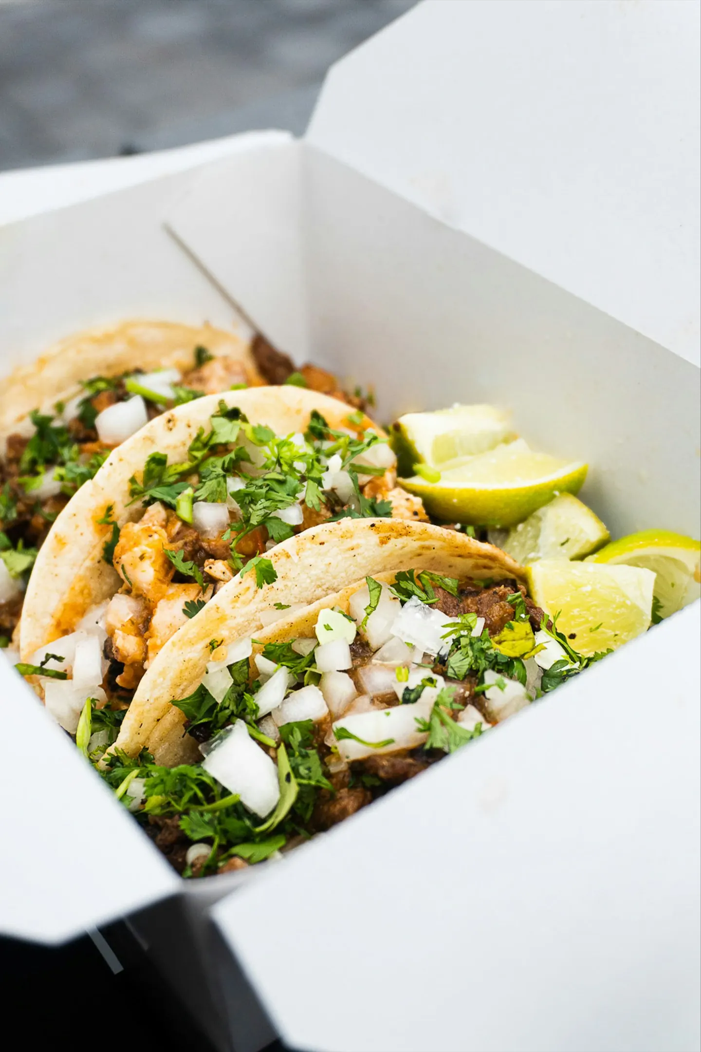 Three tacos with lime wedges