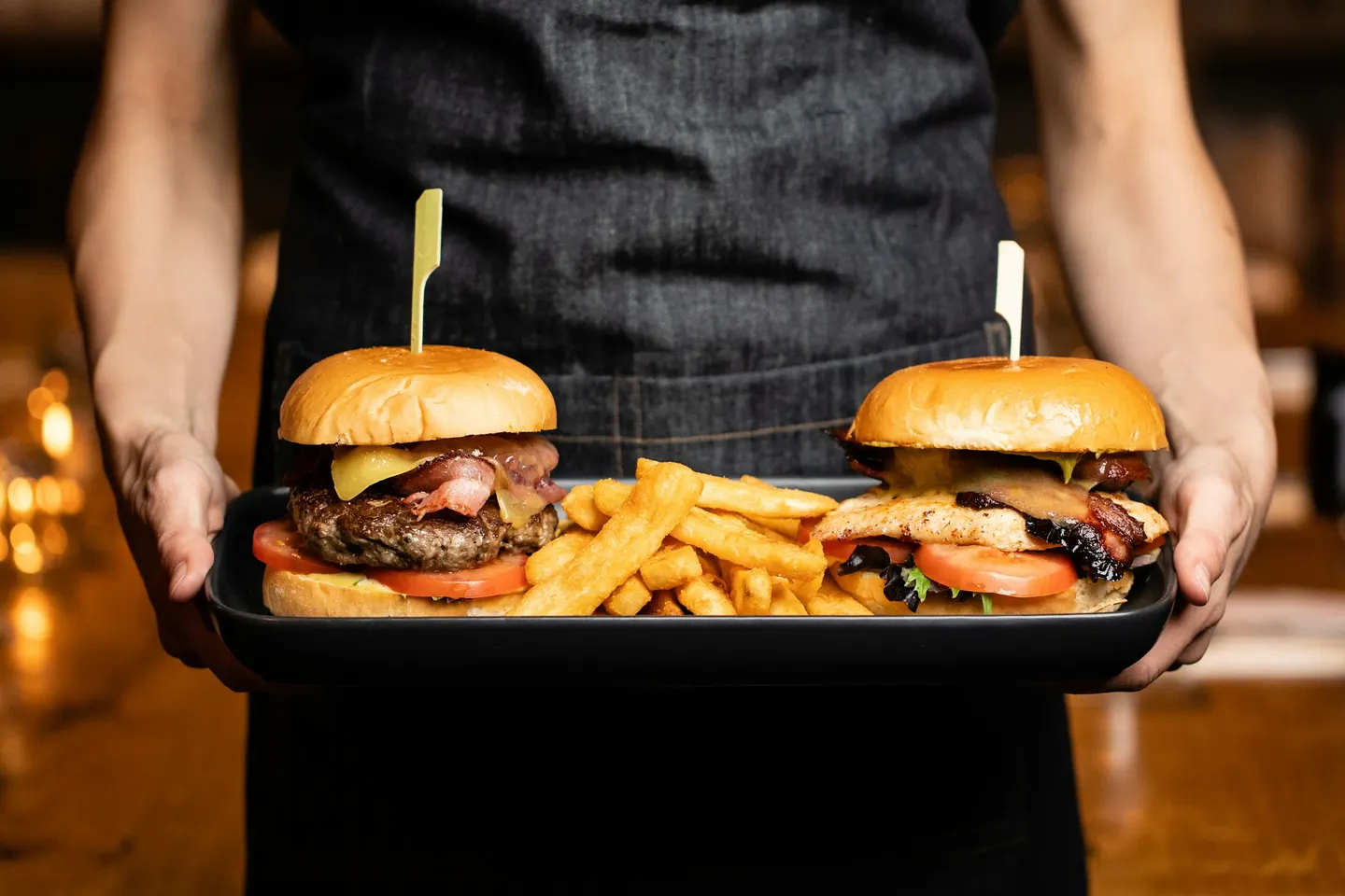 Tray of burgers and fries held by a server