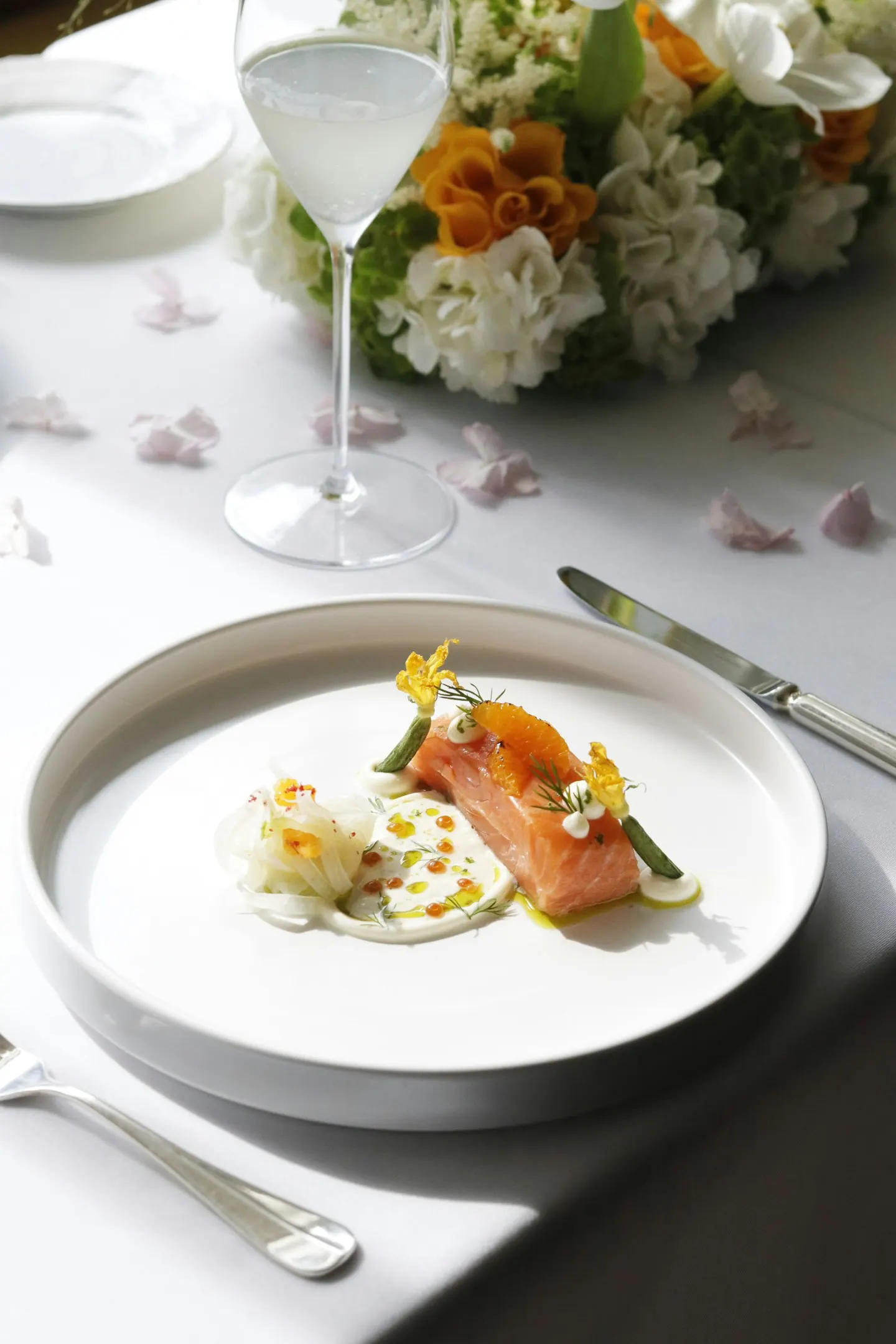 A plated seasonal dish beside a glass and flowers