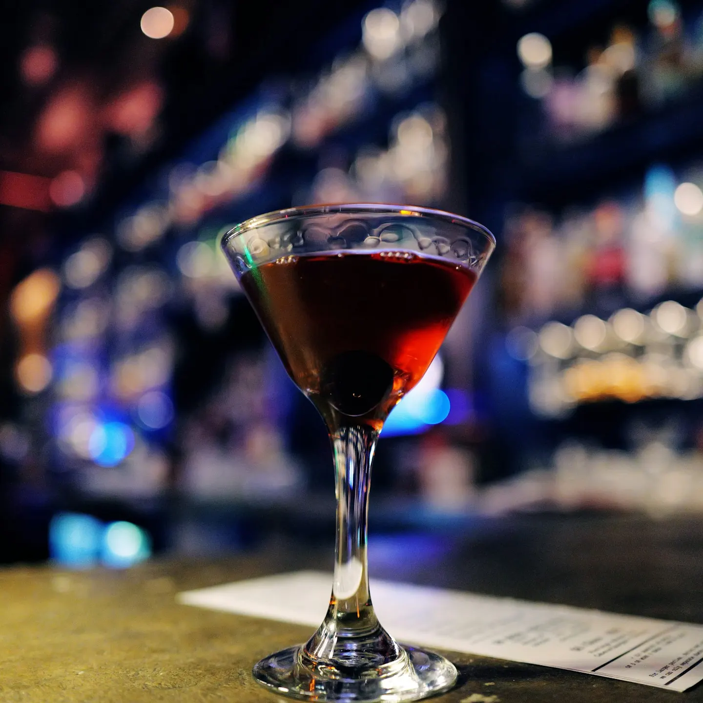 Dark cocktail with a cherry in a stemmed glass