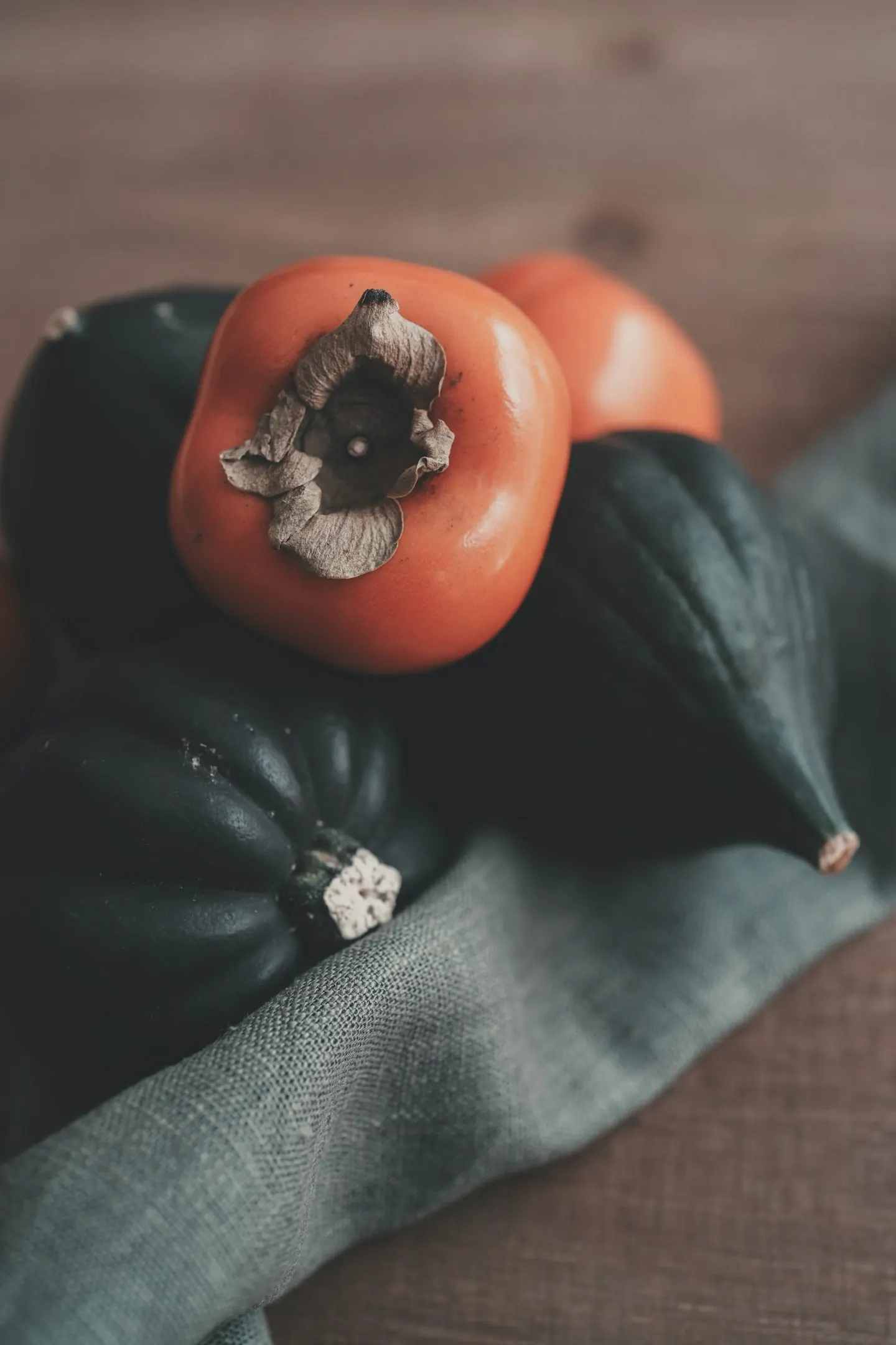 Persimmons and dark green squash in soft seasonal light